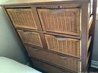 Front angle shot showing six wicker drawers each with leather pulls on wood frame