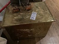 Metal kindling box with embossed pattern and wood lining on top surface.