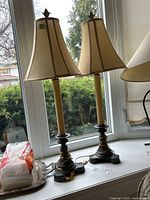 Pair of vintage-style lamps with metal bases and fabric shades on a window ledge