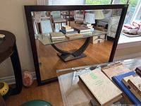 Front and angled view of a large wood framed beveled glass mirror, showing the dark brown frame and thickness of the mirror.