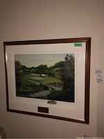Framed Brampton Golf Club print hung on the wall, showing colorful golf course landscape in a wooden frame with white matting and plaque.