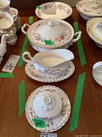 Overview of Royal Albert Jubilee Rose china serving pieces arranged on a table: covered butter dish, gravy boat with saucer, and covered serving bowl.
