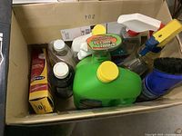 Box containing various cleaning supplies such as spray bottles, liquid cleaners, brush, and a box of Arm & Hammer powder