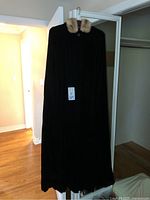 Full-length black velvet vintage ladies cape displayed hanging, showing overall appearance and length