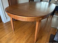 Oval table top with one leaf installed, showing fluted tapered legs and carved rosette on apron