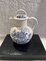 Photo showing the front side of the Crown Devon porcelain tea pot with detailed blue floral pattern on white background, including the spout and handle.