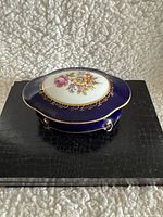 Top view of oval Echt Kobalt porcelain trinket box with cobalt blue, gold pattern and floral design on lid.