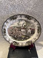 Full front view of 12-inch porcelain Johnson Bros platter showing village scene with houses, church, trees, and floral border