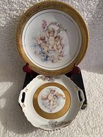 Front of plates showing cherub and floral artistry with gold detailing