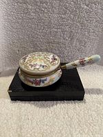 Side view of vintage Japanese porcelain floral decorative bowl with lid and handle, showing floral and gold accent details.