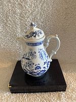 Front view of vintage Kahla teapot showing blue floral design on white porcelain with ornate handle and lid.