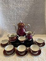 Complete coffee set displayed on black stand, showing all 14 pieces including teapot, sugar bowl, creamer, 6 cups and 6 saucers.