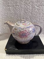 Front and side views of the teapot showing detailed floral patterns and purple coloration.