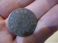 Close-up photo of the reverse side of the 1859 One Cent coin showing the denomination and date surrounded by a wreath design.