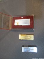 Three metallic vintage lighters, one in a red velvet presentation case with transparent lid, and two without cases.