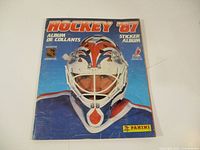 Front cover of the 1987 Panini Hockey Sticker Album featuring a hockey goalie in blue and red protective gear and mask.