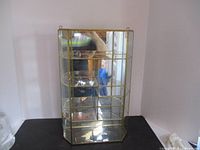 Full view of brass and glass showcase from front, showing five shelves and brass framing.