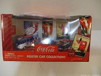 Front view of Coca-Cola Poster Car collection box showing three collectible cars and box artwork.