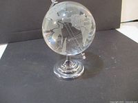 Crystal glass globe viewed from the Europe and Brazil side, showing frosted continent outlines and silver base.