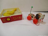 Photo showing the red and yellow wind-up record player toy alongside the pull toy dog on wheels.