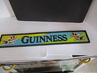 Full length view of Guinness bar runner with rubber nubs and pelican logos on blue and yellow background.