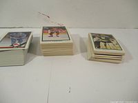 Three stacks of hockey cards placed side-by-side showing differing thicknesses and card backs/edges, representing separate series in the lot.