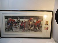 Wide shot of framed print, matted scene with two cards on right, black frame under cracked glass