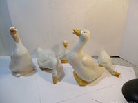 Set of five ceramic ducks on a white surface, various poses and sizes