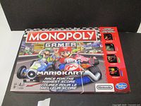 Front of the Monopoly Gamer Mario Kart Edition box featuring Mario and Luigi racing and visible character pieces for Mario, Princess Peach, and Luigi.