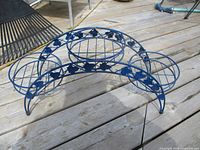 Side angle view of the blue metal plant stand showing the three rounded pot holders and the lattice design underneath.