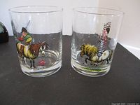 Close-up frontal photo of two glasses showing Norman Thelwell cartoon illustrations of horse and rider, and donkey with frog.