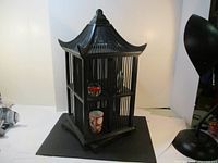 Front and side views of the black wooden pagoda-shaped storage unit placed on a white backdrop, showing its tiered shelves and curved roof design.