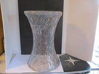 Front view of clear plastic plant stand showing geometric faceted pattern and shape
