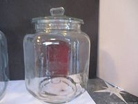 Clear glass jar with lid, showing embossed 5 cent mark on base