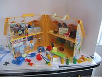 Full view of foldable Playmobil house with figures and furniture pieces arranged inside and outside