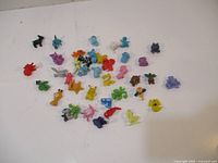 39 small Pokémon figures scattered on a white surface showing various colors and species.