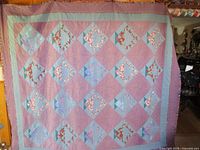 Full view of the quilt showing overall patchwork diamond pattern with floral and pastel fabrics.