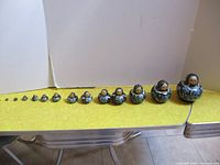 Full set of 14 Russian nesting dolls lined up from smallest to largest on a yellow table.