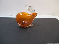 Front and side view of amber-colored studio art glass rabbit figurine with clear ears and feet.
