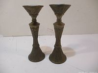 Pair of brass candle sticks standing upright side by side, showing overall shape and design