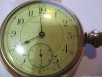 Front close-up of vintage pocket watch face with Arabic numerals and sub-second dial.