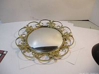 Full view of the round convex bubble dome mirror in a decorative metal frame with floral accents.
