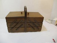 Closed vintage wooden sewing basket with top handle, showing the compact form and wood finish.