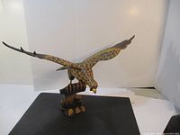 Full side view of the carved wooden eagle with wings spread resting on a carved wooden tree stump base, showing size and overall design.