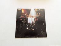 Front view of ABBA Super Trouper album cover showing band members on stage under spotlight with audience around.