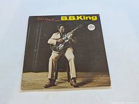 Front cover of B.B. King Great Moments vinyl LP showing B.B. King seated playing guitar in beige suit against dark background.