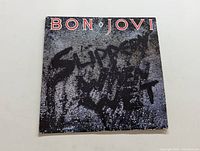 Front cover of Bon Jovi 'Slippery When Wet' vinyl LP showing the stylized wet surface design and band name.