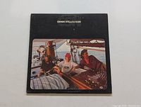 Front cover of Crosby, Stills & Nash vinyl LP showing band seated on a sailboat outdoors.