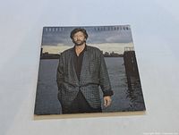 Front cover of Eric Clapton LP "August" showing Eric Clapton in a patterned jacket near water.
