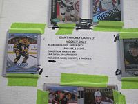 Top view of taped backing board with multiple hockey cards surrounding a printed lot sheet detailing multi-era brands included